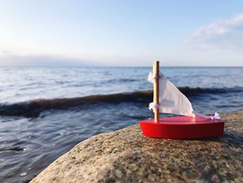 Boat on rocks by sea against sky