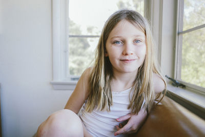 Thoughtful girl sitting on sofa by window at home