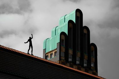 Low angle view of sculpture on building roof at hochzeitsturm tower against cloudy sky