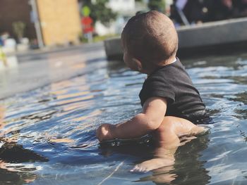 Full length of baby boy sitting in pond