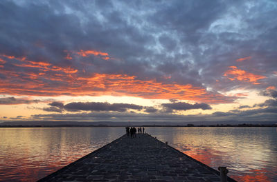 Pier over lake against sky during sunset