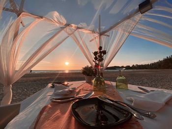 Ferris wheel on beach against sky during sunset