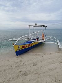 Boat moored on beach against sky