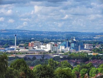 City by river against cloudy sky