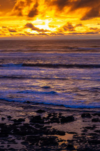 Scenic view of sea against dramatic sky during sunset