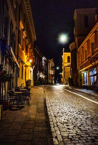 Illuminated street amidst buildings at night