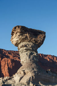 Low angle view of rock formation against clear blue sky