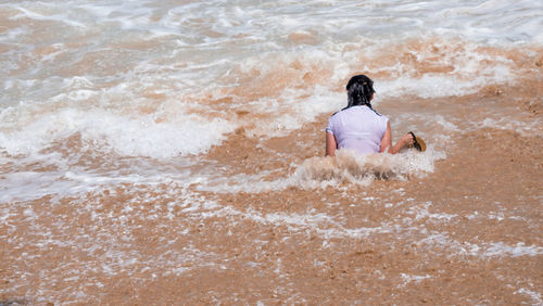 Rear view of woman sitting on beach