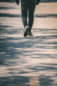 Low section of person walking on road in city