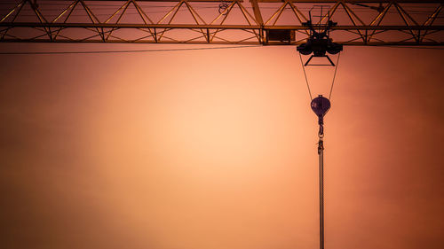 Silhouette crane against orange sky during sunset