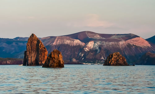 View of rocks in sea against cloudy sky