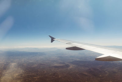 Airplane flying over landscape against blue sky