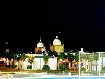 Illuminated buildings against clear sky at night