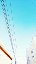 Low angle view of electricity pylon against clear blue sky