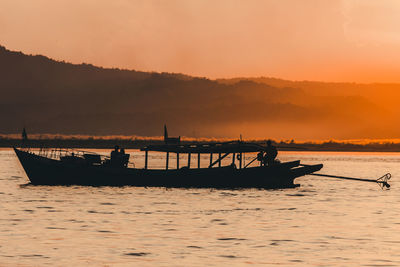 Silhouette boat in sea against sky during sunset