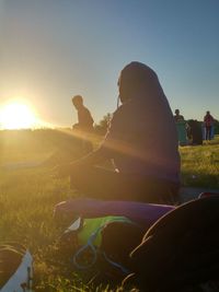 Woman sitting on field against clear sky