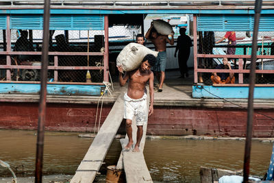 Full length of shirtless man standing on bridge