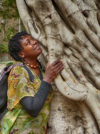 Close-up of woman standing by tree trunk