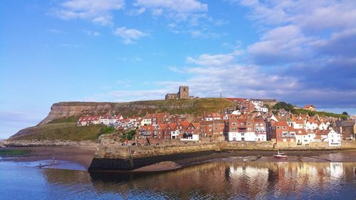 Buildings by sea against blue sky