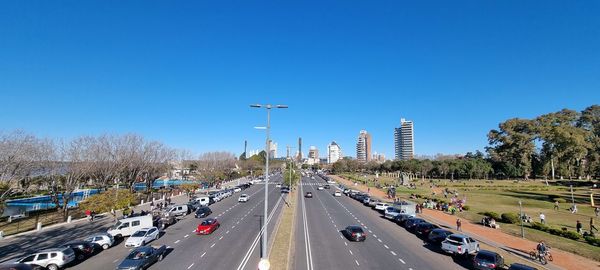 Vehicles on road in city against clear blue sky