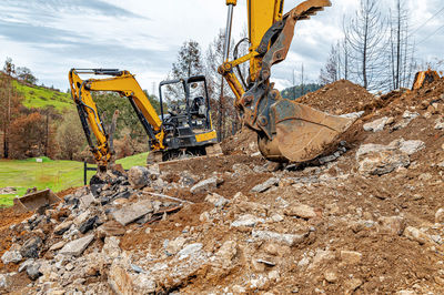 Extraction of natural building materials. excavators in quarry. background blue sky, mountains