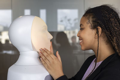 Smiling woman looking at robot voice assistant