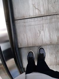 Low section of person standing on escalator