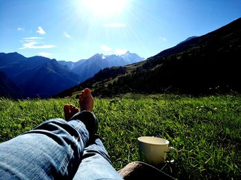 Low section of woman sitting on landscape against mountains