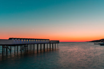 Pier over sea against clear sky during sunset