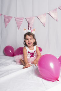 Happy girl with balloons on bed