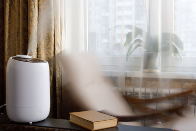 White air humidifier increases air humidity. near motion rocking chair. houseplant on background