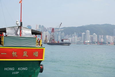 Nautical vessel on sea by city against clear sky