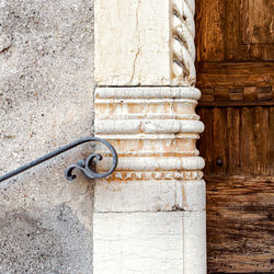 Close-up of closed door on wall, ancient railing and marble decoration