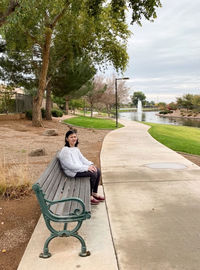 Rear view of woman sitting on bench in park