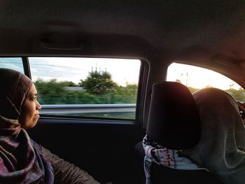 Rear view of woman looking through car window