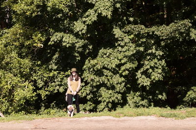 Woman standing with dog on land against plants