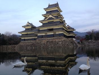 Built structure by lake against sky