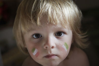 Close-up portrait of cute boy with chicks painted with green white and red colours