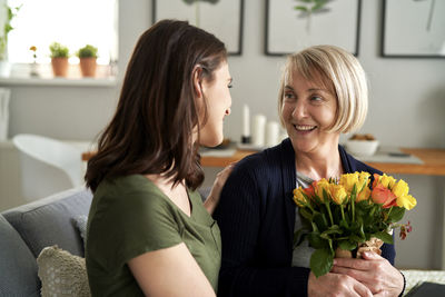 Side view of young woman with bouquet at home