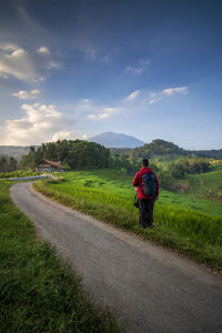 Rear view of woman walking on road against sky