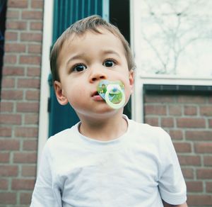 Portrait of boy with pacifier against wall