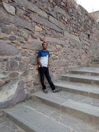 Full length portrait of young man standing against wall