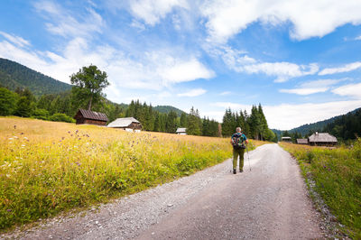 Rear view of man walking on road against sky