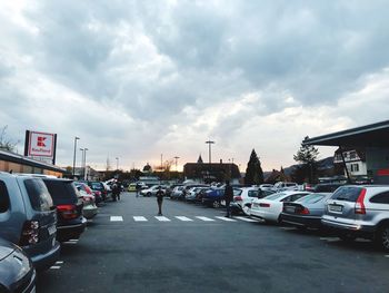 Traffic on road in city against cloudy sky