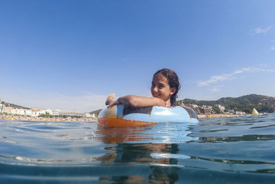 Portrait of young woman swimming in sea against sky