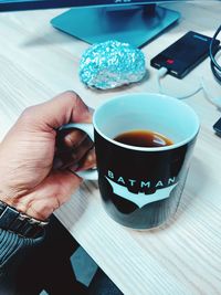 Cropped image of person holding coffee cup on table