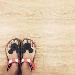 Low section of woman wearing shoes on hardwood floor