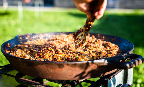 Close-up of man preparing food on barbecue grill in yard