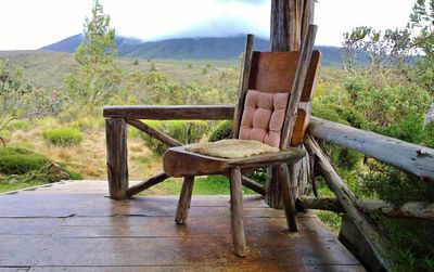 Empty chairs and table against trees on landscape