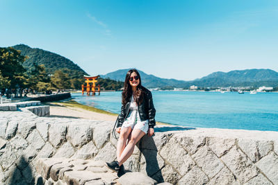 Portrait of woman on rock against blue sky